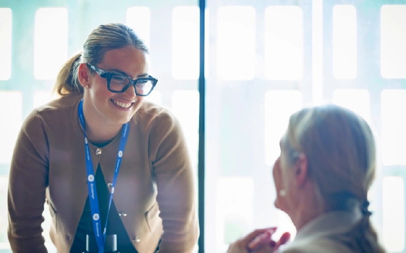 Bizzdesign employee wearing glasses speaking with a colleague in a bright office.